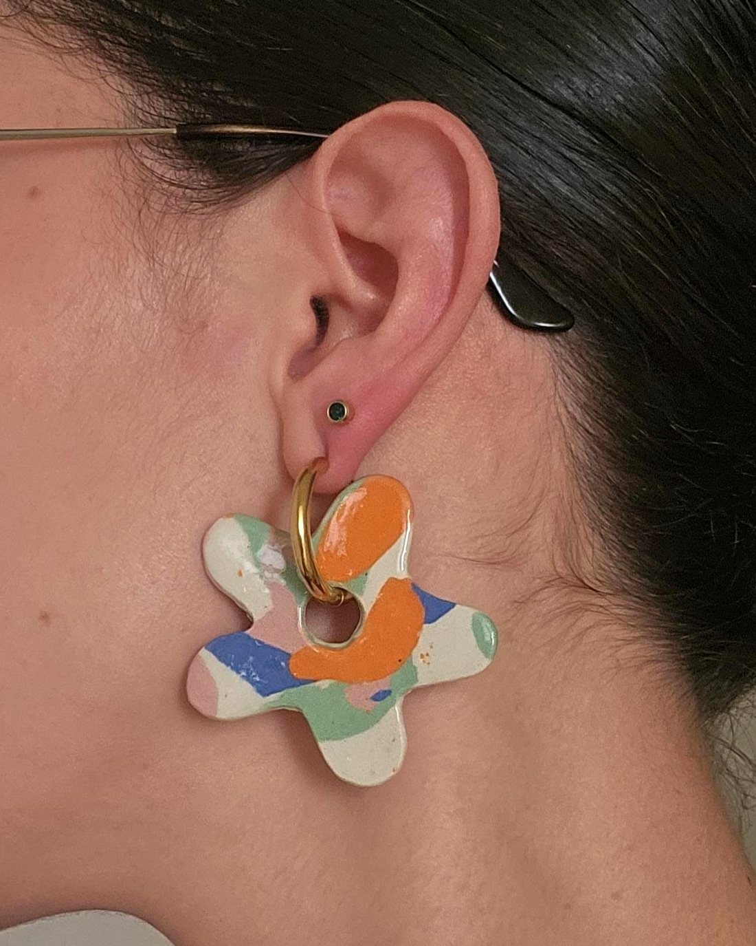 Model wearing a colourful ceramic flower earring on a gold hoop