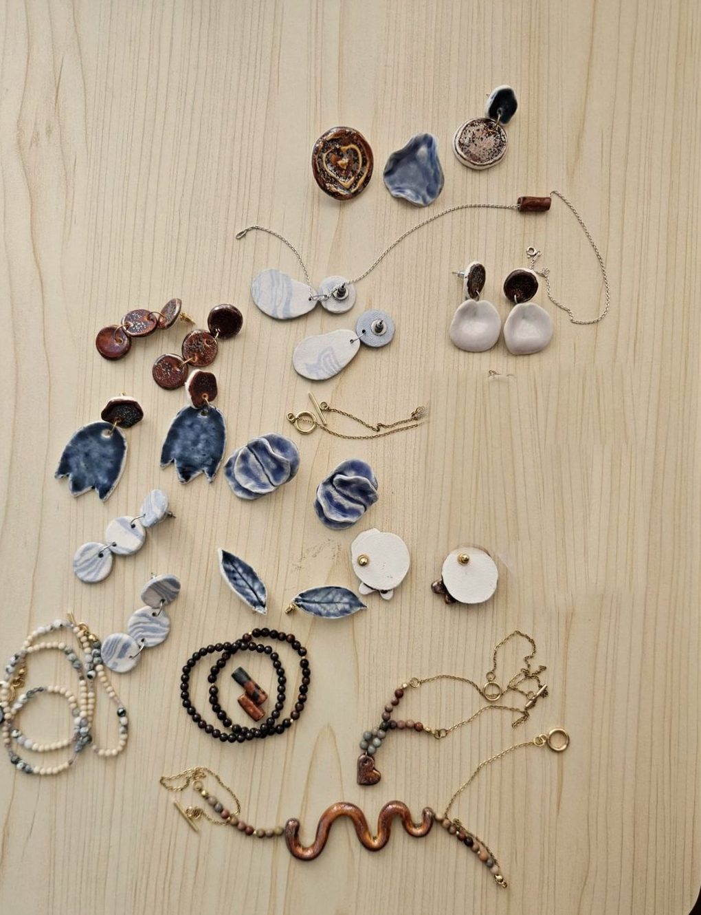 Flat-lay of ceramic earrings, necklaces and bracelets on wood